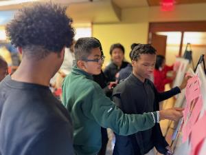 group of students placing sticky notes on whiteboard